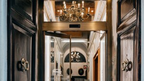 A hotel entrance with a wooden door, a red doormat, and a chandelier. - Hotel Pantheon (Rome)