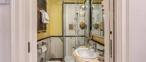 Un baño con ducha de mampara de vidrio, lavamanos y bidé.