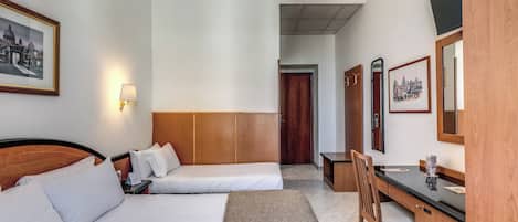 A hotel room with two beds, a desk, a chair, a lamp, a mirror, and a framed picture on the wall.