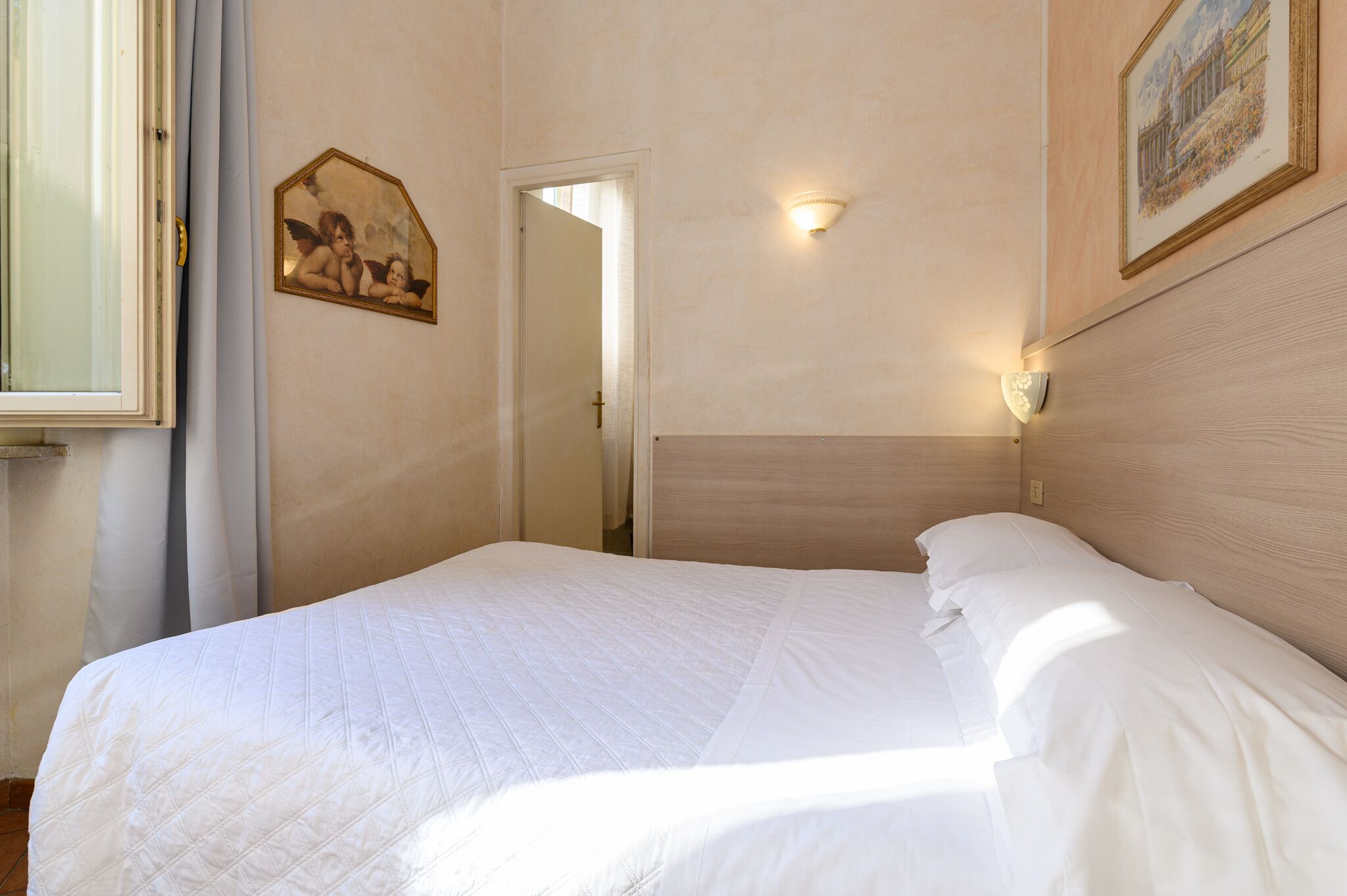 A neatly made bed in a room with a wooden headboard, a framed picture on the wall, and a door leading to another room.