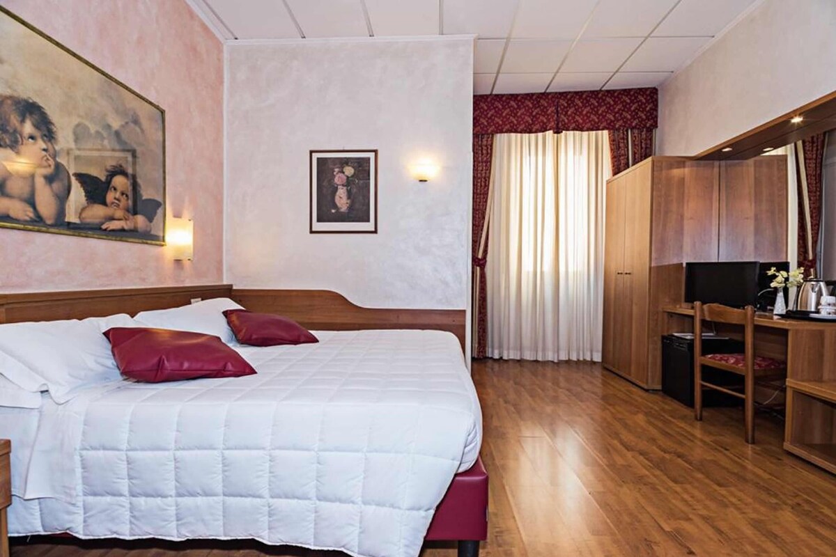 Habitación de hotel con una cama grande, un escritorio, un armario y un cuadro en la pared.