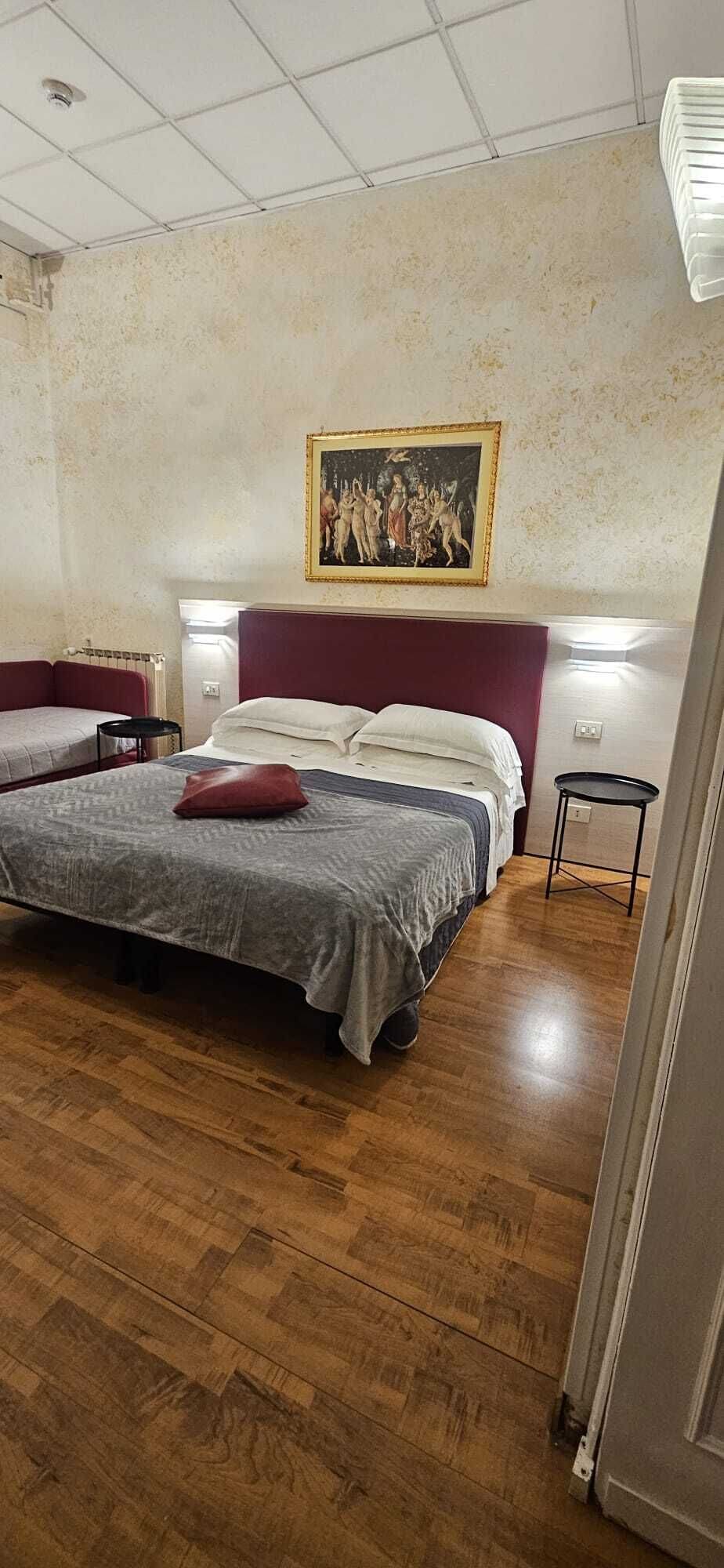 Une chambre à coucher avec un lit, une table de chevet, une chaise, un tableau au mur et un plancher en bois.