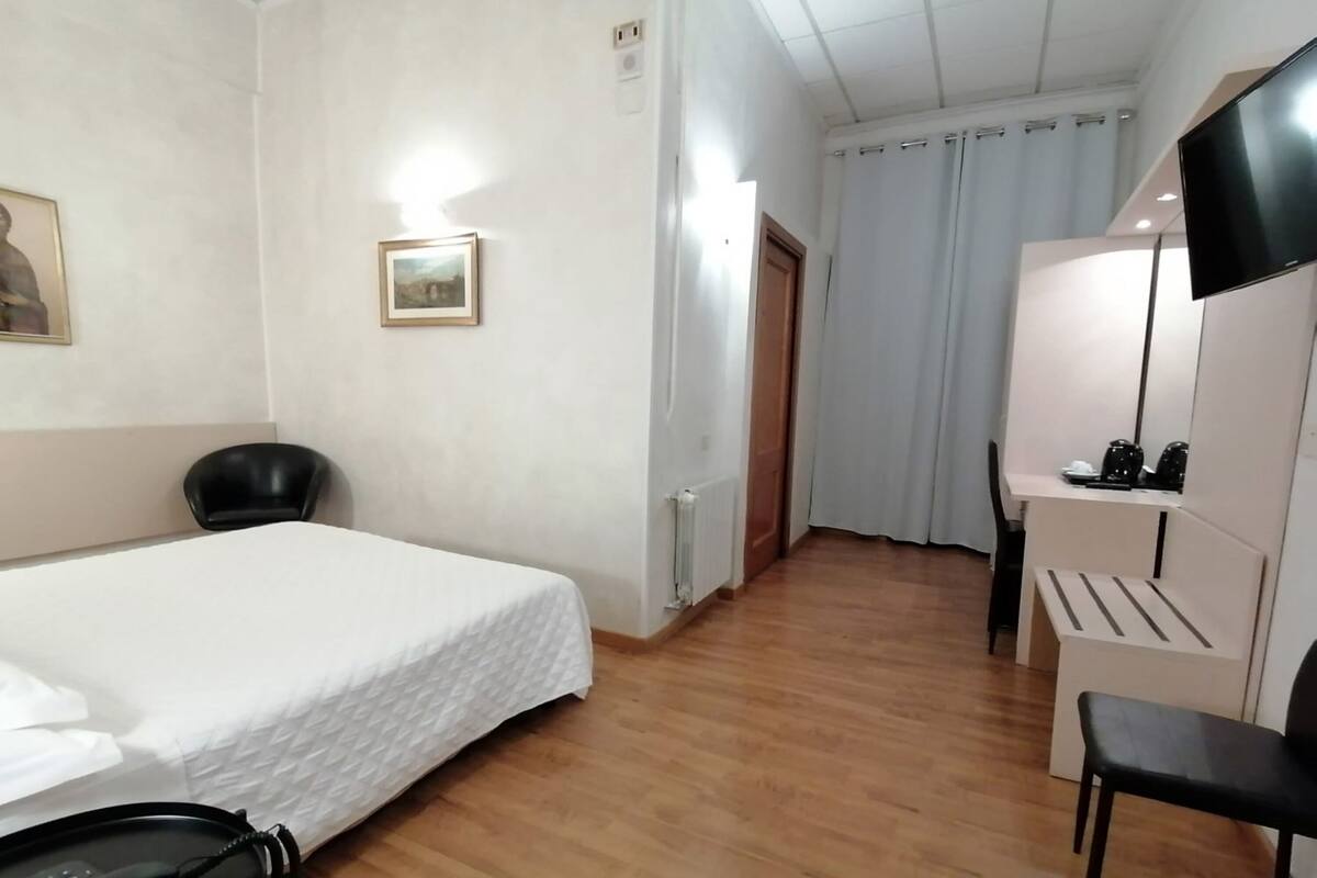 Habitació d'hotel amb llit, escriptori, cadira, telèfon i televisió.