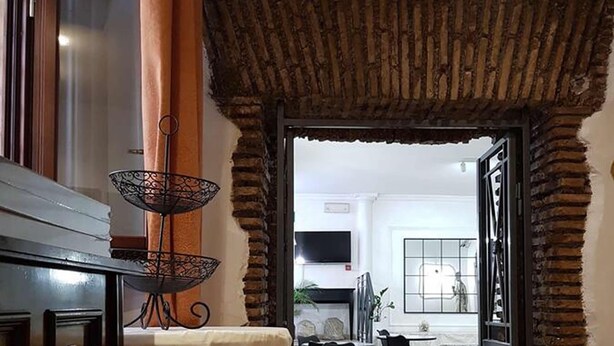 Un comedor con una mesa de madera, sillas y un estante metálico decorativo.