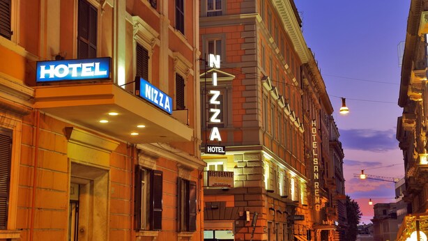 Un hôtel appelé « HÔTEL NIZZANA », avec une enseigne indiquant la présence d’un restaurant au rez-de-chaussée.