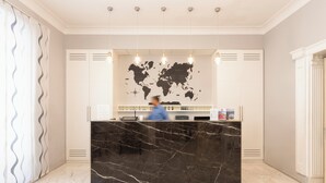 A reception desk with a world map, a marble counter, and a person behind it. - Hotel Virgilio (Rome)