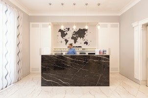 A reception desk with a world map, a marble counter, and a person behind it.