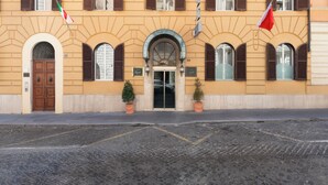 A building with a symmetrical facade, arched windows, and a central entrance with a door. - Hotel Virgilio (Rome)