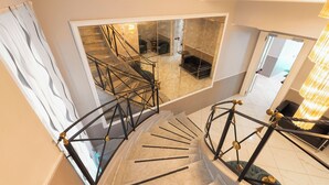 A spiral staircase with a modern design, leading to a living area with a sofa and a coffee table. - Hotel Virgilio (Rome)
