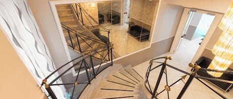 Una escalera de caracol con diseño moderno que conduce a una sala de estar con un sofá y una mesa de centro.