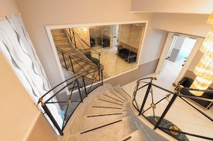 A spiral staircase with a modern design, leading to a living area with a sofa and a coffee table.
