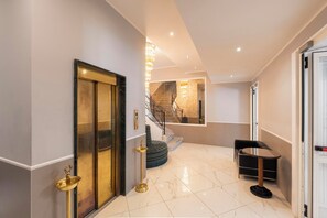 Un interno moderno con pavimento in marmo, una scala, un tavolo rotondo e una porta con maniglia dorata.