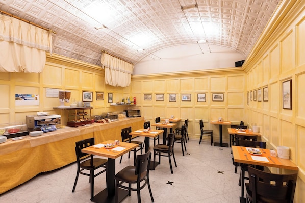 Zona pranzo con buffet, tavoli, sedie e soffitto decorato.