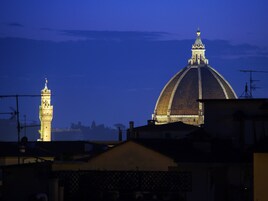 Vista noturna de um edifício histórico com uma cúpula imponente e uma torre alta.