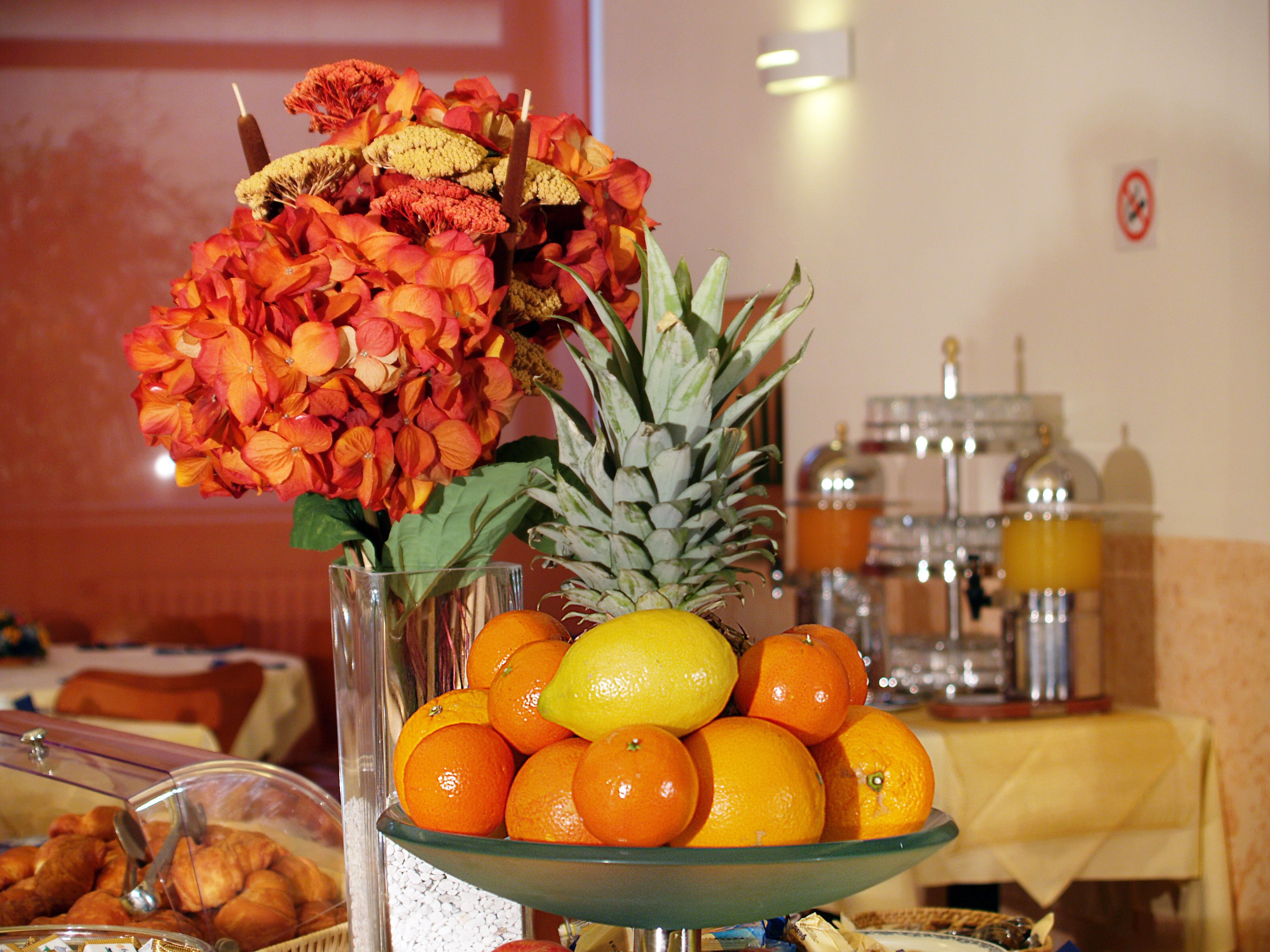 Un buffet agrémenté d’un saladier rempli d’oranges et d’un vase de fleurs.