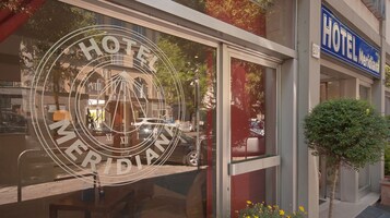Una finestra di hotel con un grande logo circolare che presenta numeri romani e la scritta 'HOTEL'.