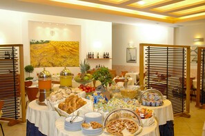 Una mesa de buffet con diversos alimentos, un cuadro en la pared e iluminación empotrada en el techo.