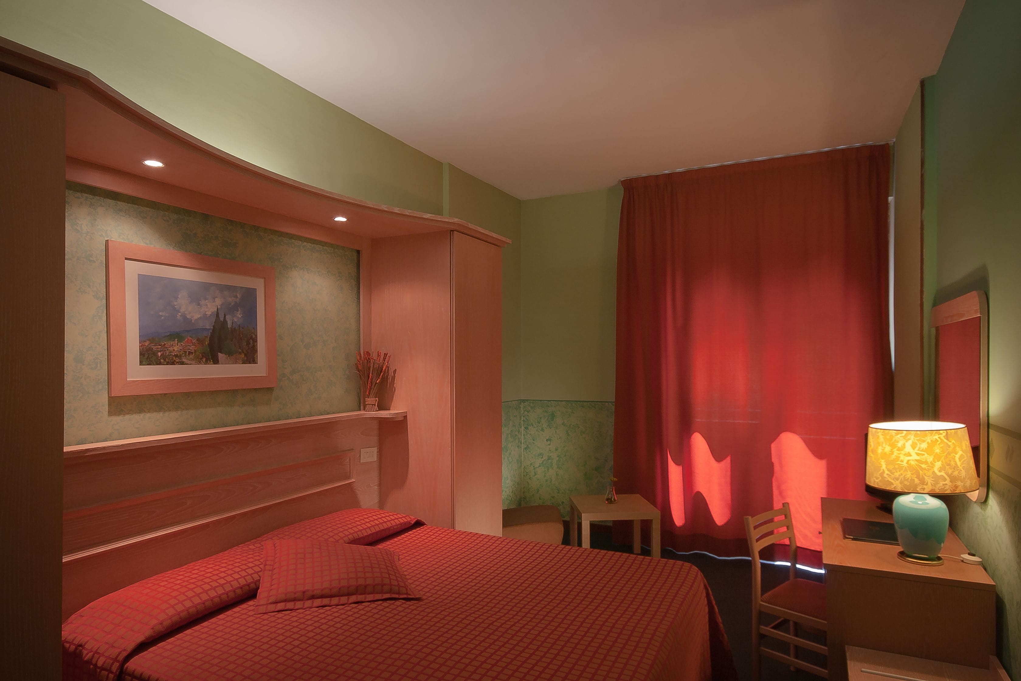 Une chambre à coucher avec un lit, un bureau avec une lampe, une chaise et un tableau au mur.