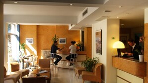 A hotel reception area with a reception desk, seating area, and a large window. - Hotel Meridiana (Florence)