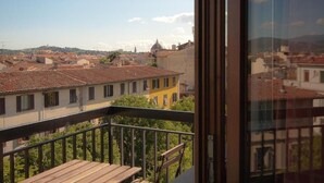 A balcony with a view of a cityscape, including buildings with red-tiled roofs and a prominent yellow building. - Hotel Meridiana (Florence)