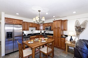 A modern kitchen with wooden cabinets, stainless steel appliances, and a dining table set for four.