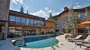 Un bâtiment moderne doté d’une piscine, d’un espace extérieur aménagé et d’une façade en pierre.