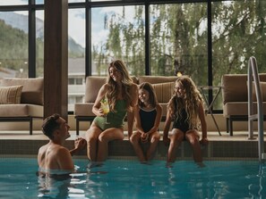 A poolside area with a view of trees and mountains, a lounge chair, and a pool.