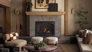 A spacious living area with a fireplace, wooden beams, a large painting, and comfortable seating. - The Kenrick Hotel  (Banff)