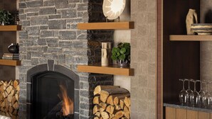 A modern interior with a stone fireplace, wooden shelves, and a dining area. - The Kenrick Hotel  (Banff)
