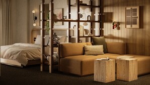 A modern hotel room with a wooden partition, a sofa, a bed, and a small wooden table. - The Kenrick Hotel  (Banff)