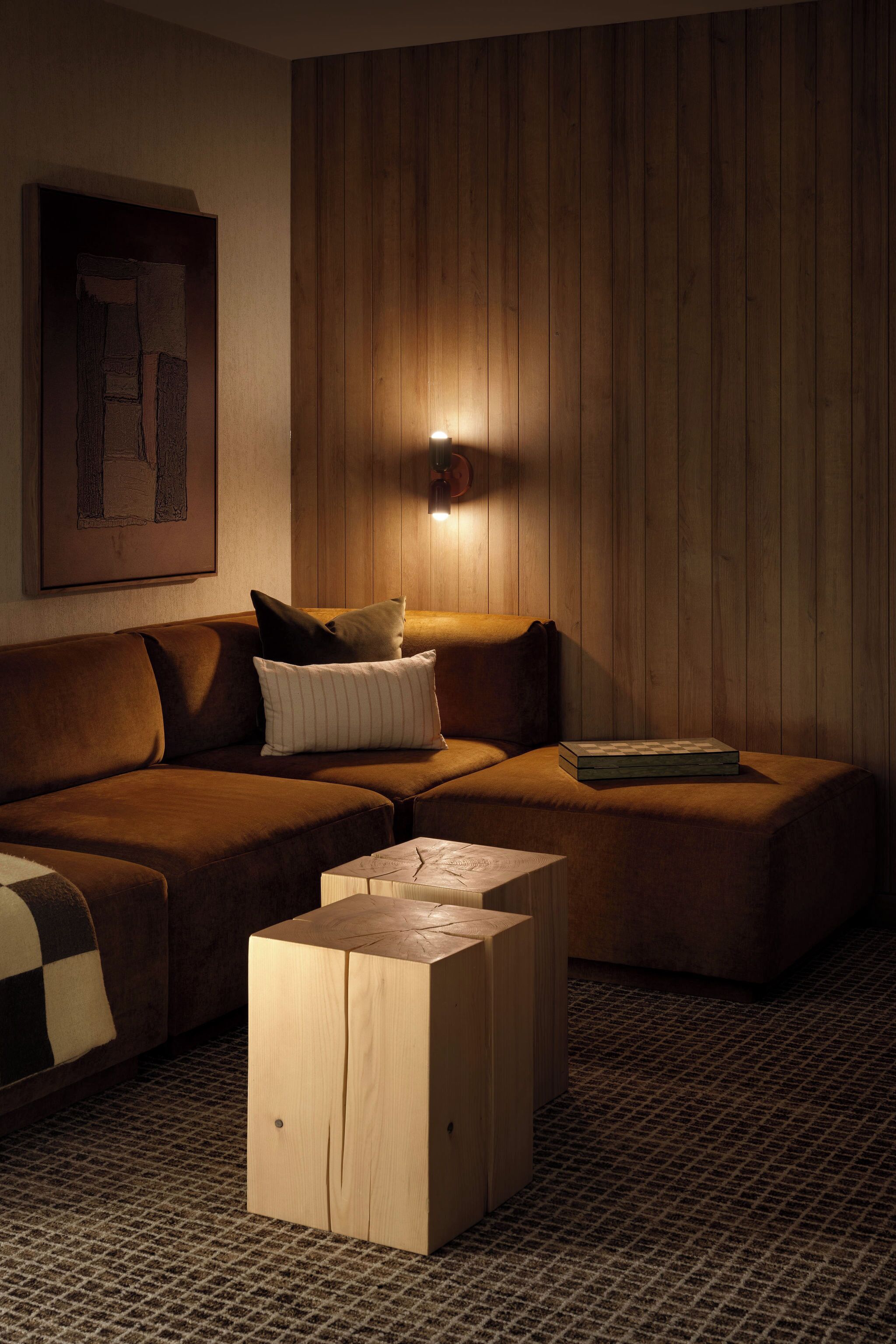 Ein gemütliches Wohnzimmer mit einer braunen Couch, einem Holztisch und einer Wandleuchte.