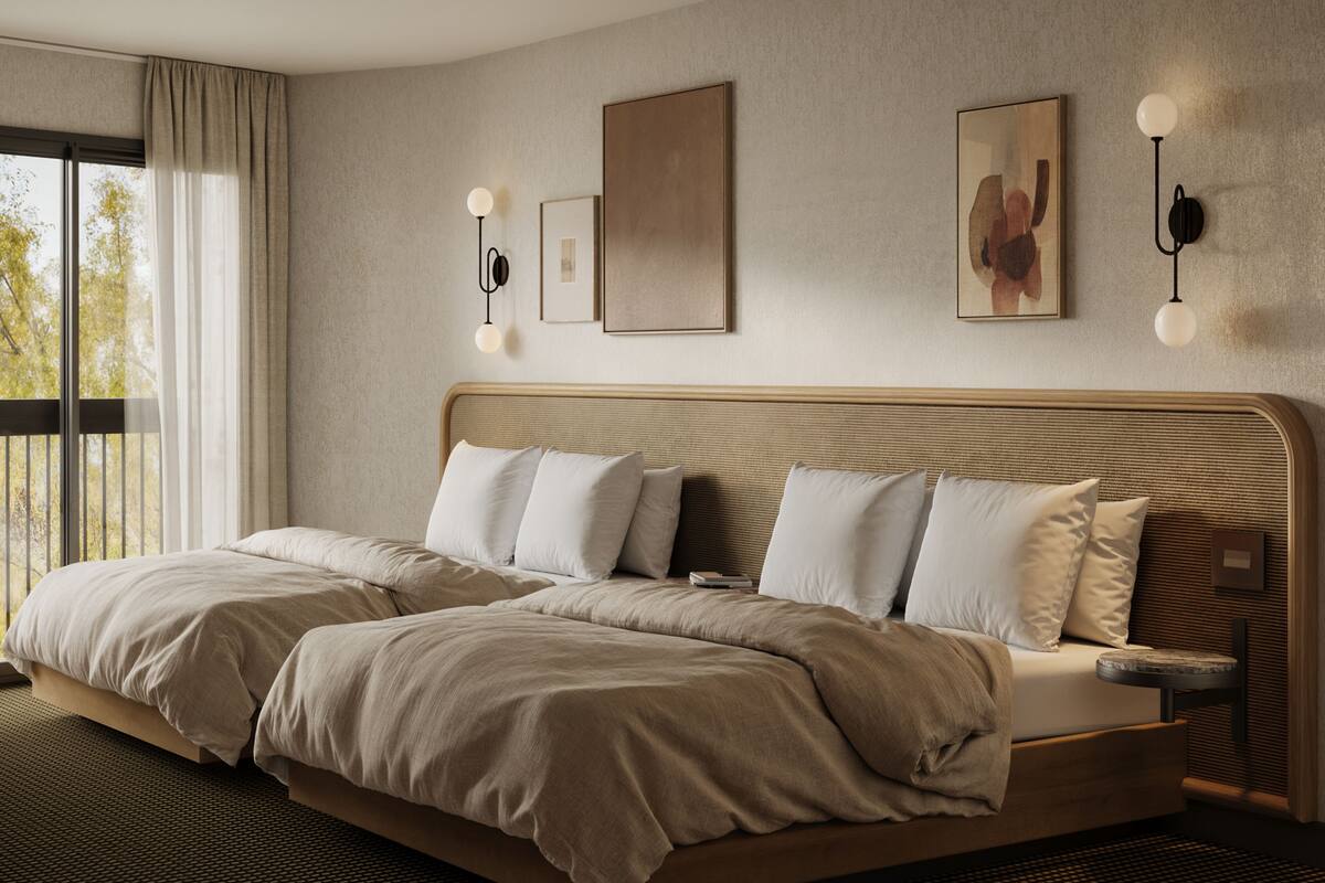 A modern hotel room with a large bed, two bedside tables, and a view of the outdoors.