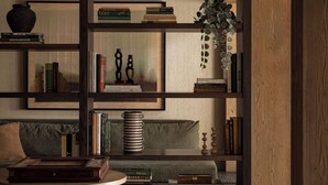A cozy room with a wooden bookshelf, a round table, and a cushioned bench. - The Kenrick Hotel  (Banff)