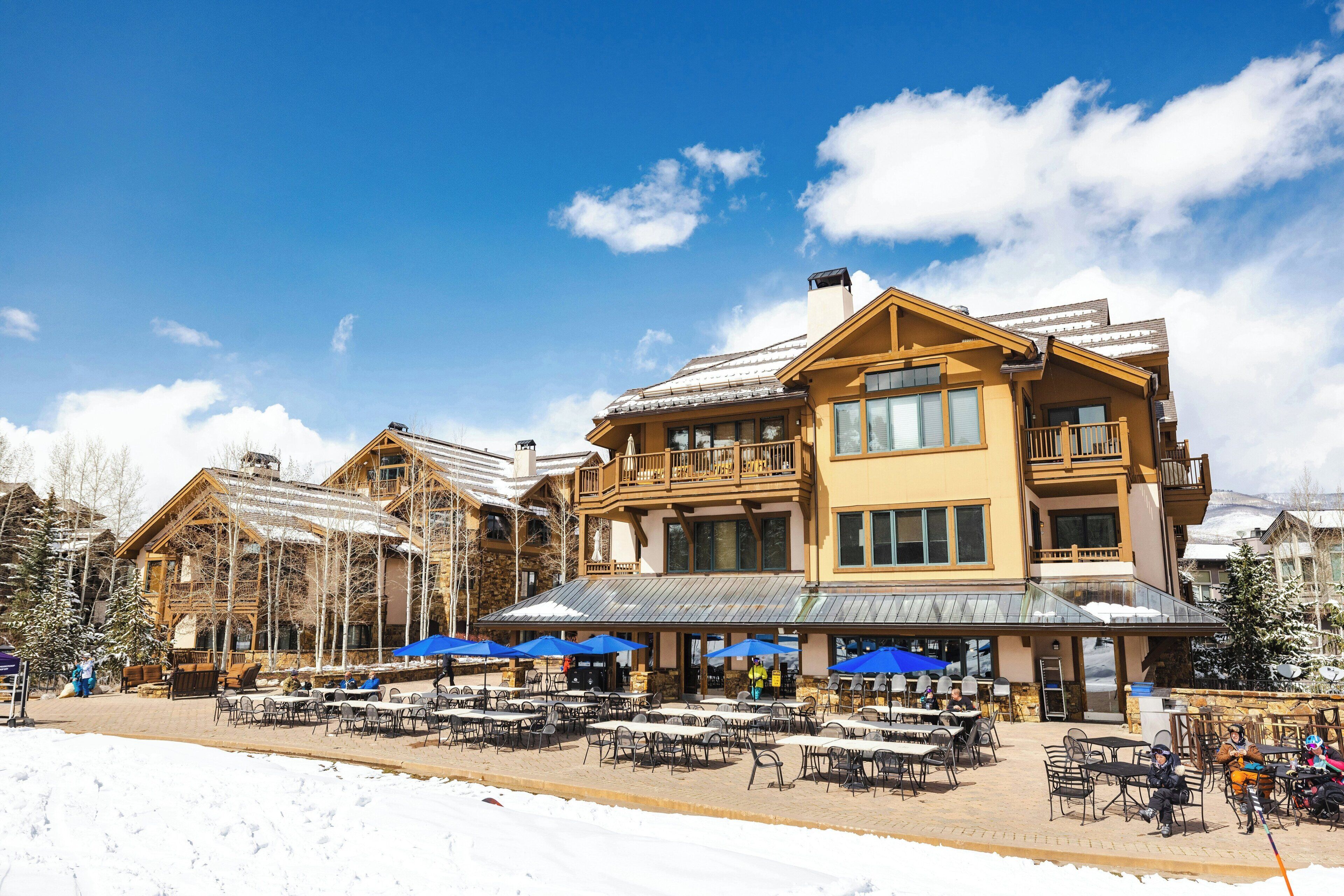 A large lodge with outdoor seating and a snow-covered ground.