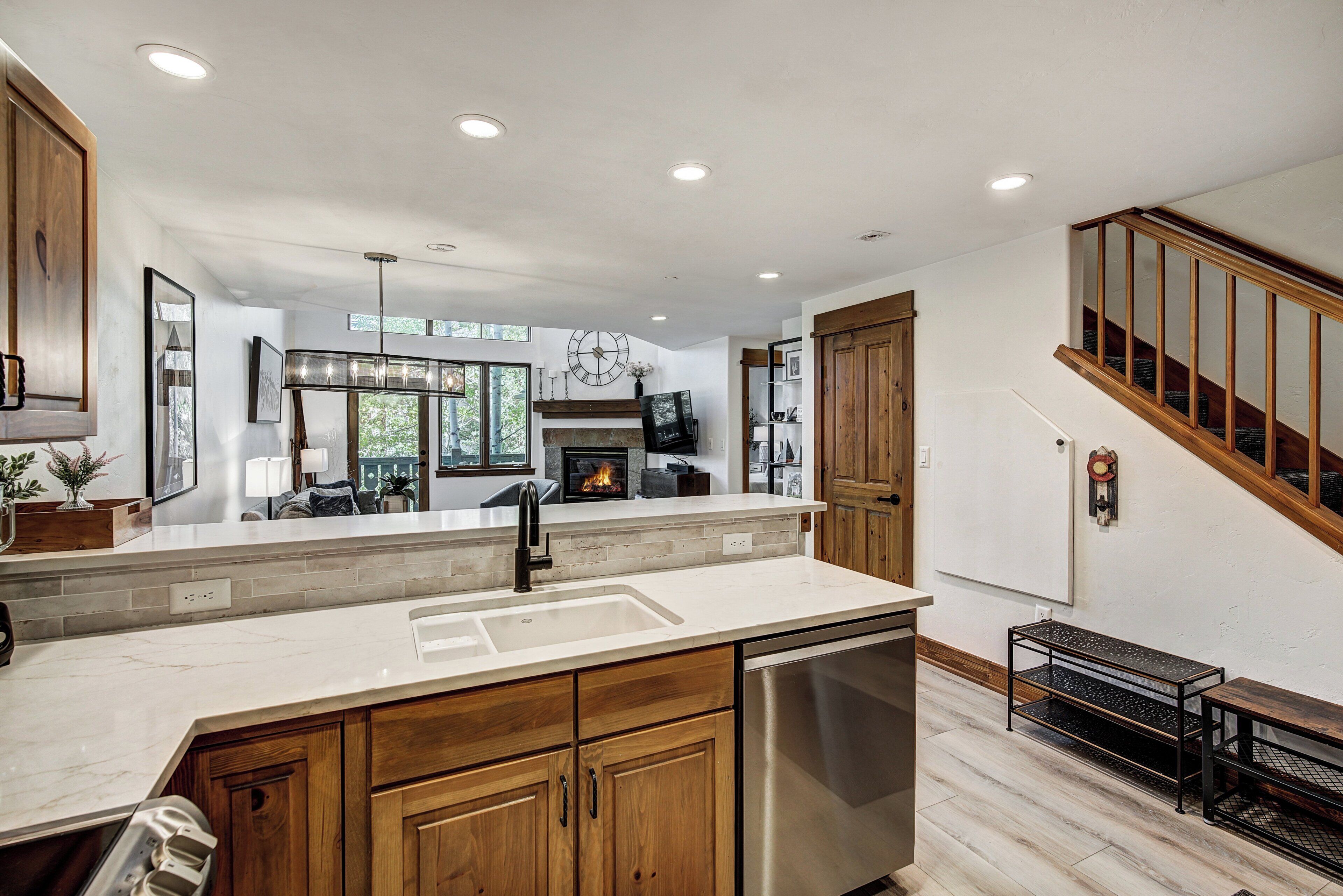 A modern kitchen with a central island, wooden cabinets, and a stainless steel dishwasher.