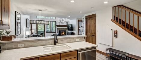 A modern kitchen with a central island, wooden cabinets, and a stainless steel dishwasher.