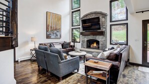 A modern living room with a stone fireplace, large windows, and a cozy seating area. - Arrowhead Village, A Vail Resorts Property (Edwards)