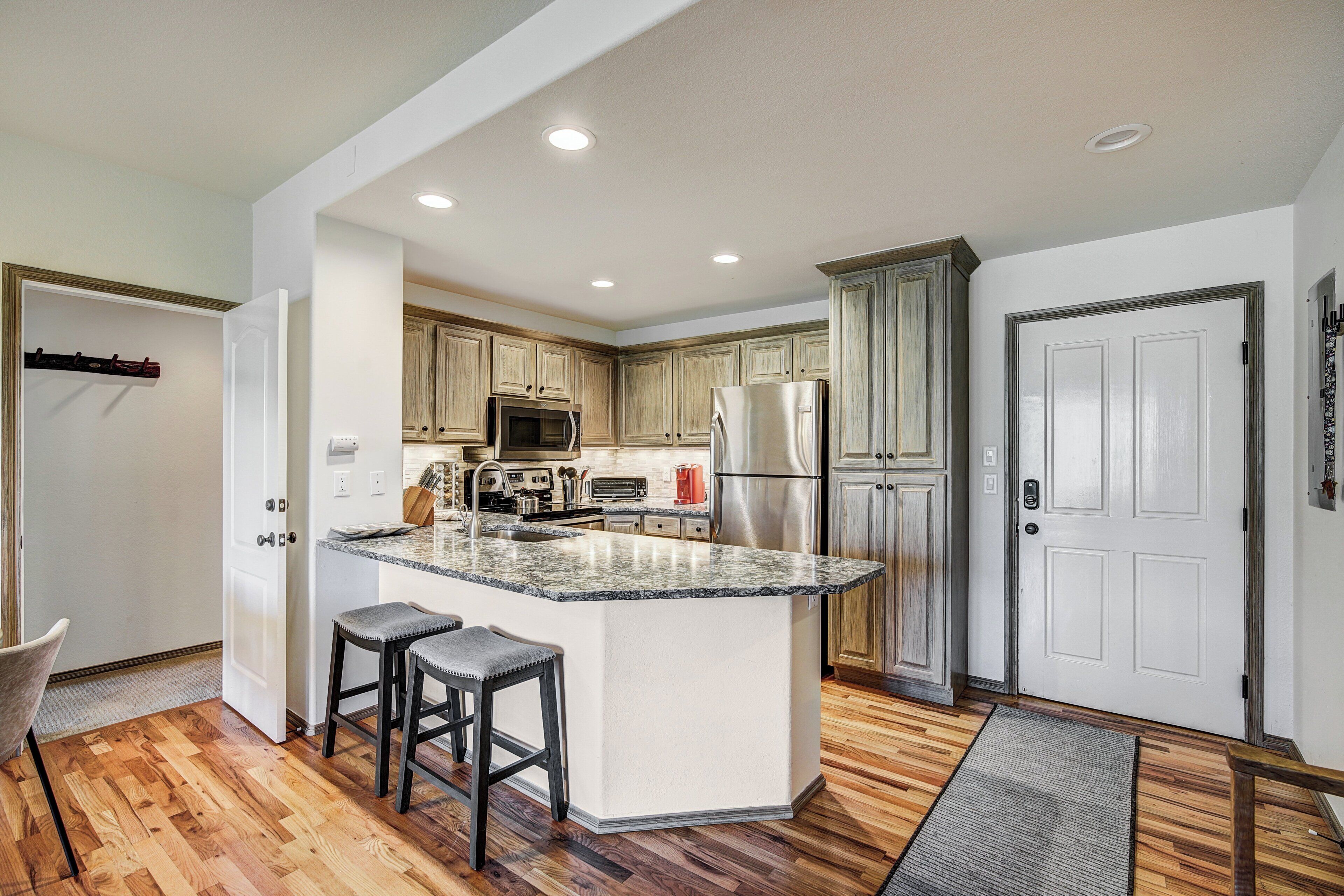 A modern kitchen with a central island, stainless steel appliances, and wooden cabinetry.