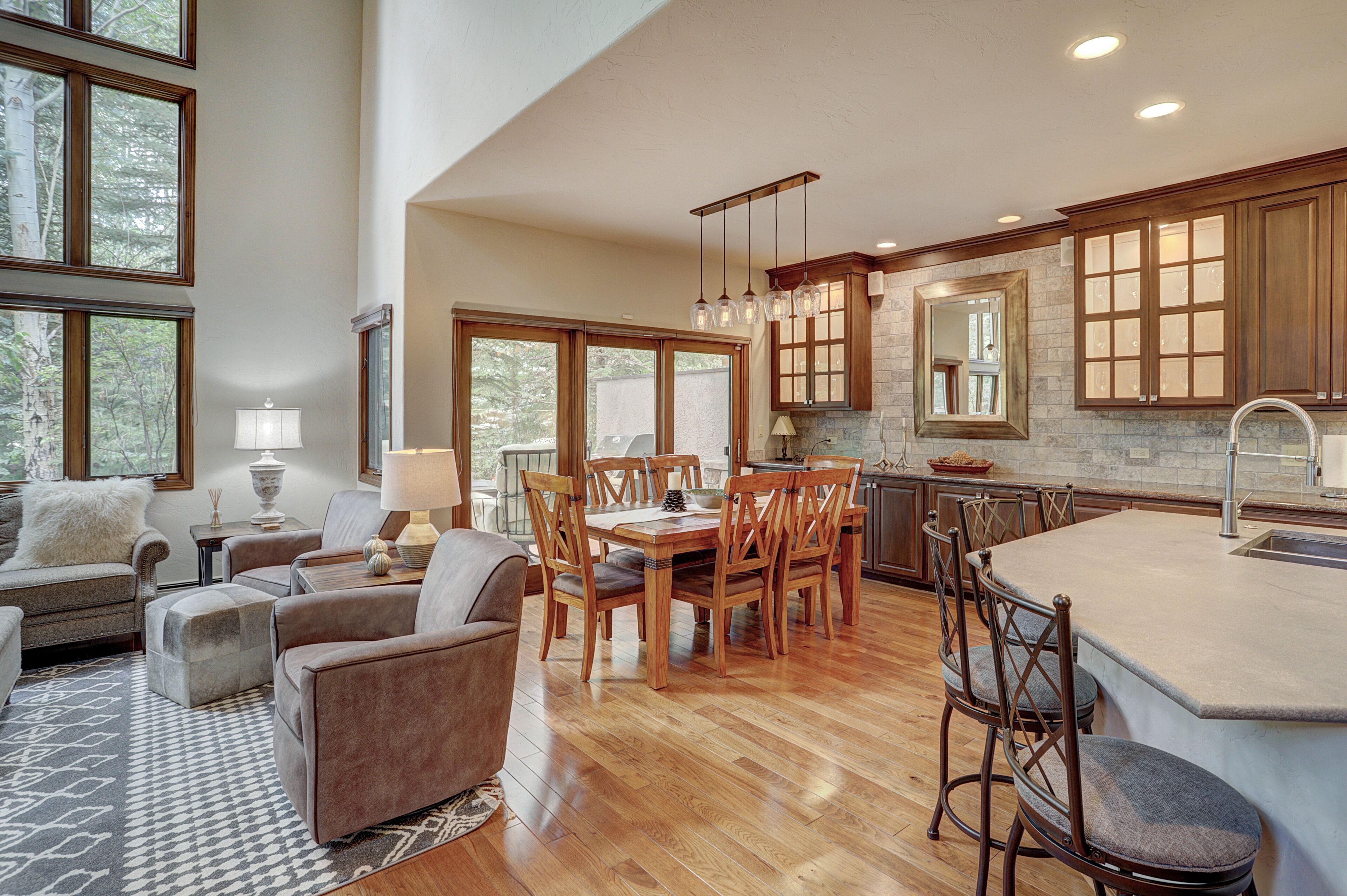 A spacious kitchen with wooden cabinets, a large island, and a dining area with chairs and a table.