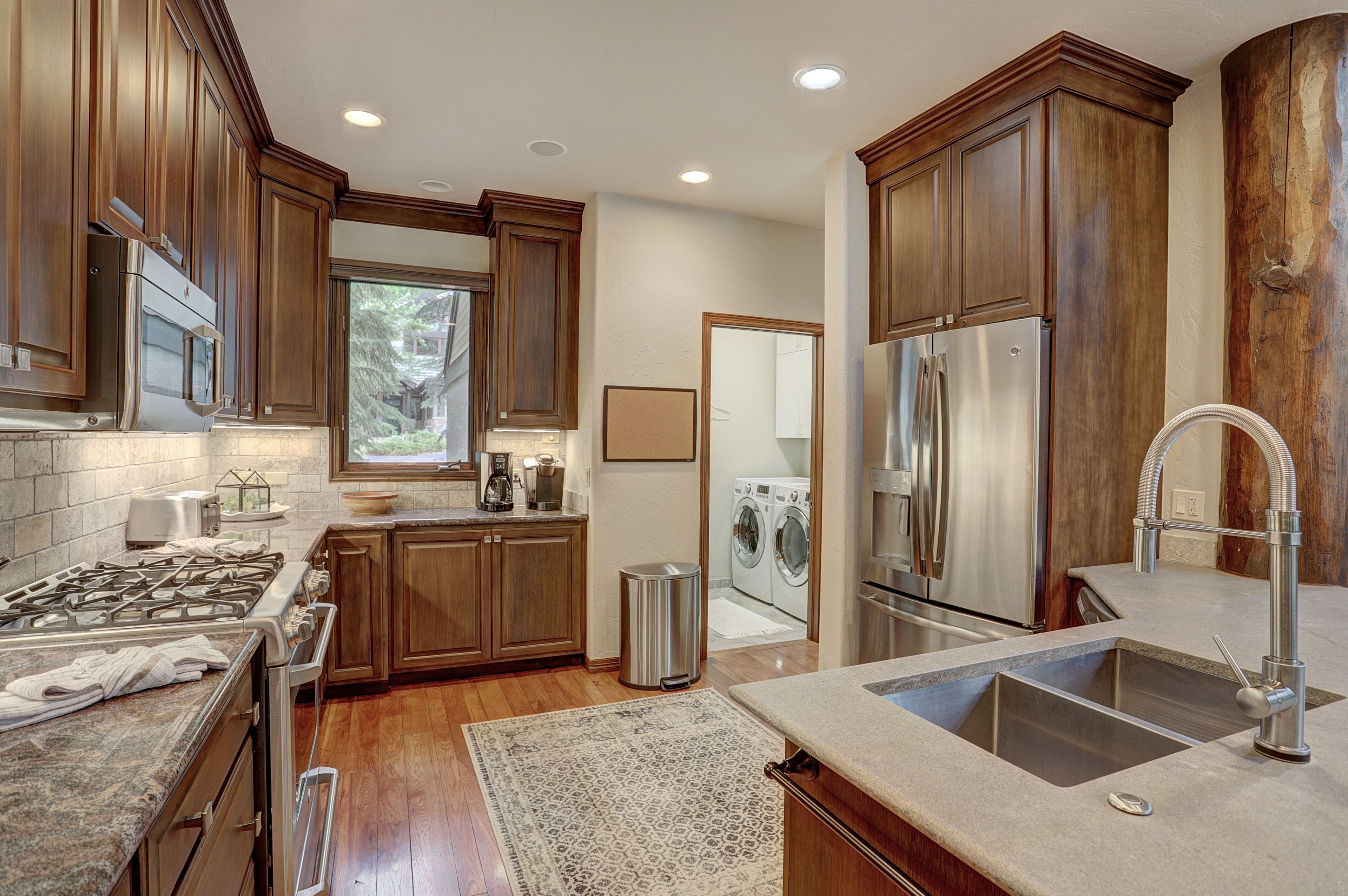 A modern kitchen with wooden cabinets, stainless steel appliances, and a large sink.