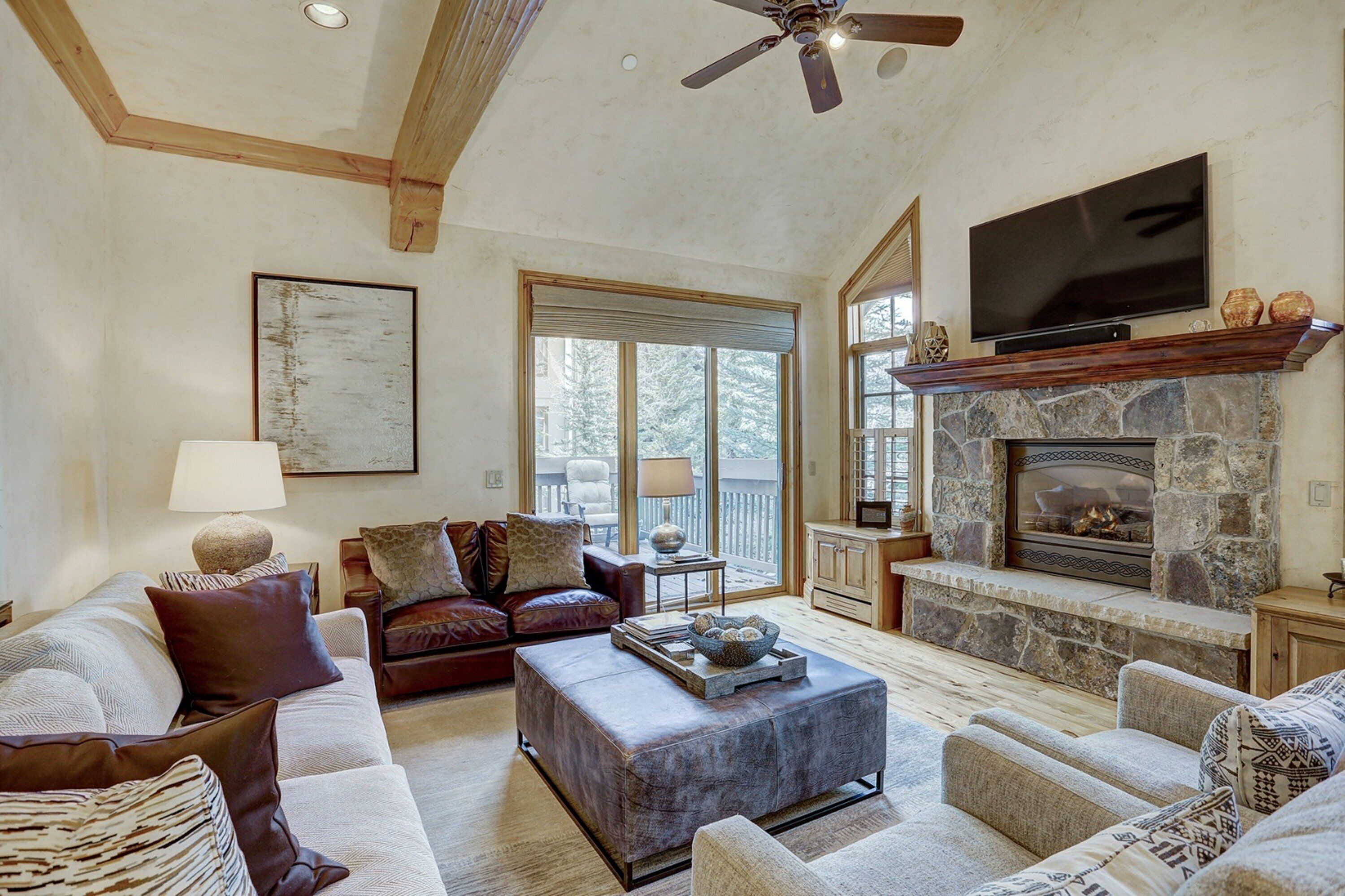 A spacious living room with a stone fireplace, a large flat-screen TV, and comfortable seating.