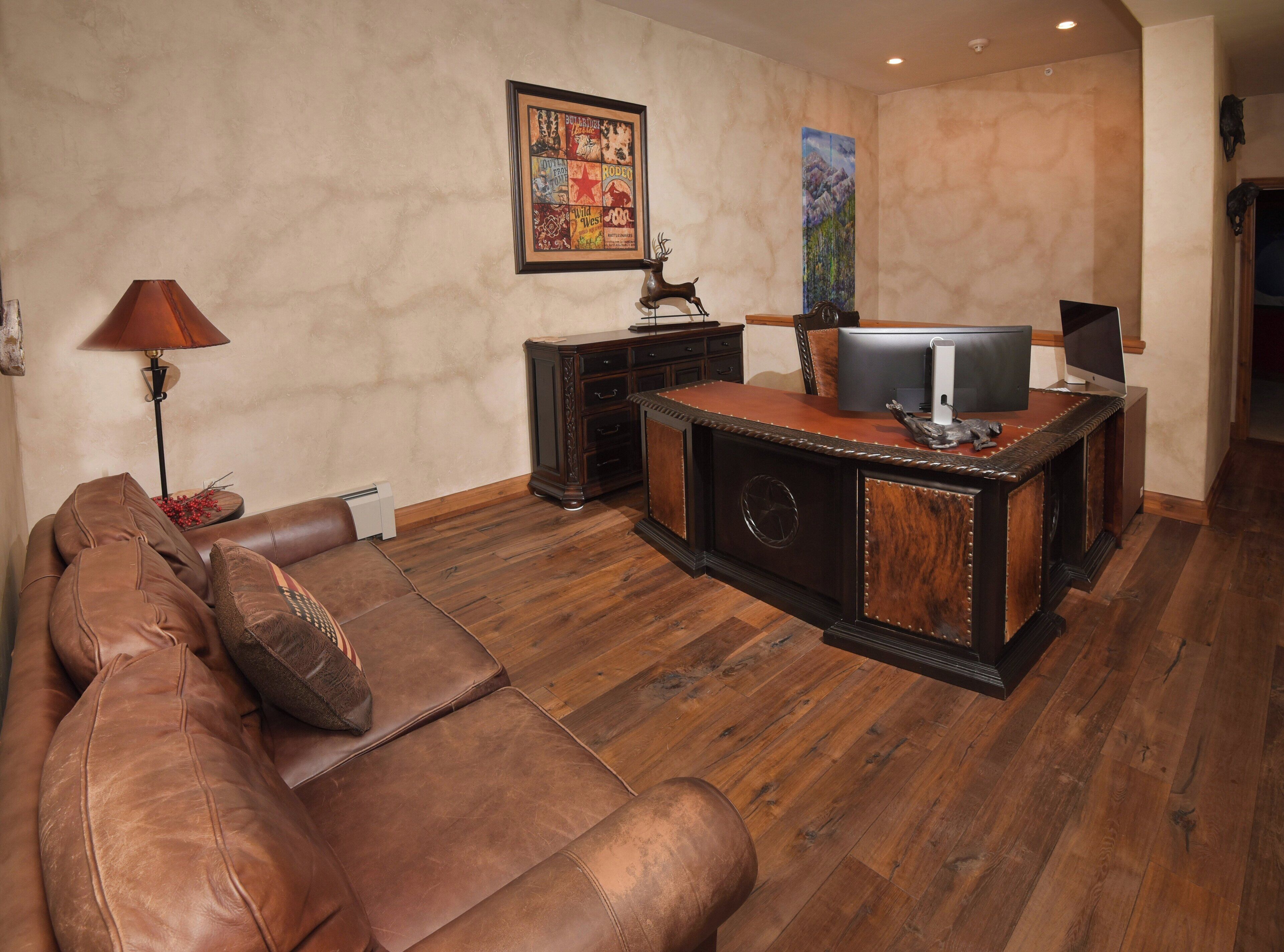 Un salon avec un canapé en cuir marron, un meuble de rangement en bois et un téléviseur fixé au mur.
