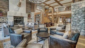 A spacious lobby with leather sofas, a stone fireplace, wooden beams, and a large deer head mounted on the wall. - Elkhorn Lodge, A Vail Resorts Property (Avon)