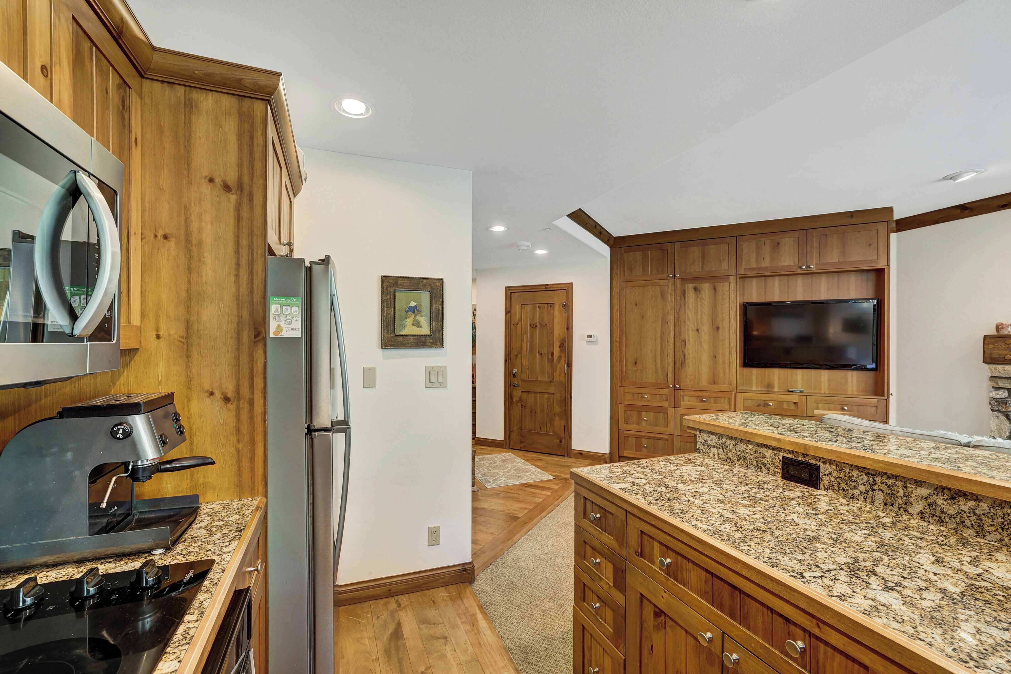 A kitchen with wooden cabinets, granite countertops, a built-in oven, and a refrigerator.