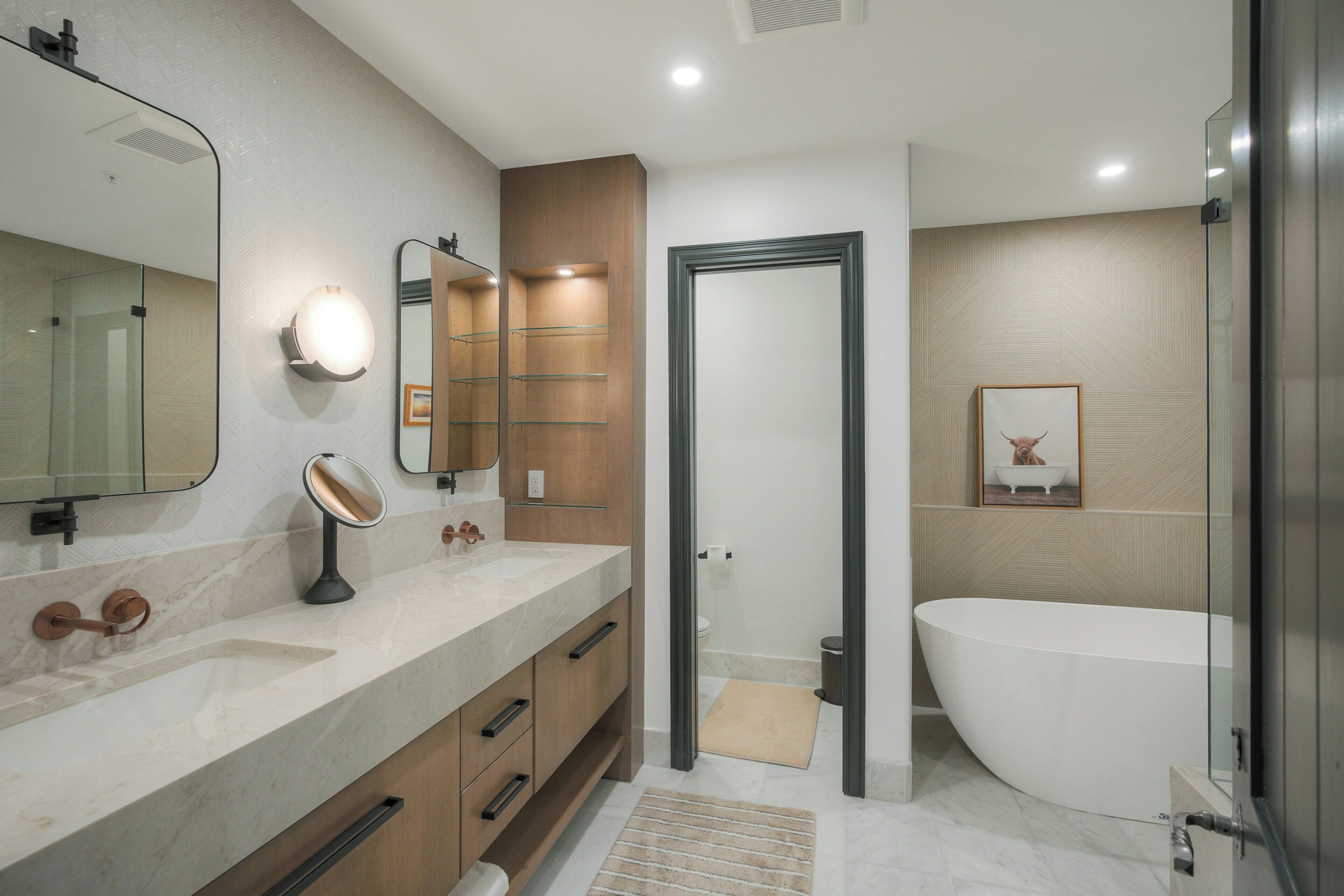 A modern bathroom with a large sink, mirror, and a freestanding bathtub.