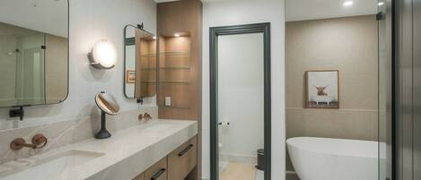 A modern bathroom with a large sink, mirror, and a freestanding bathtub.