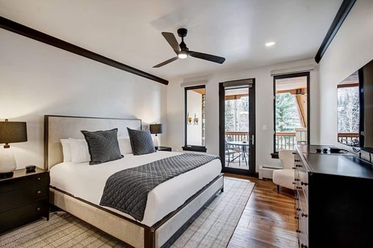 Un dormitorio moderno con una cama grande, un ventilador de techo y vistas al exterior.