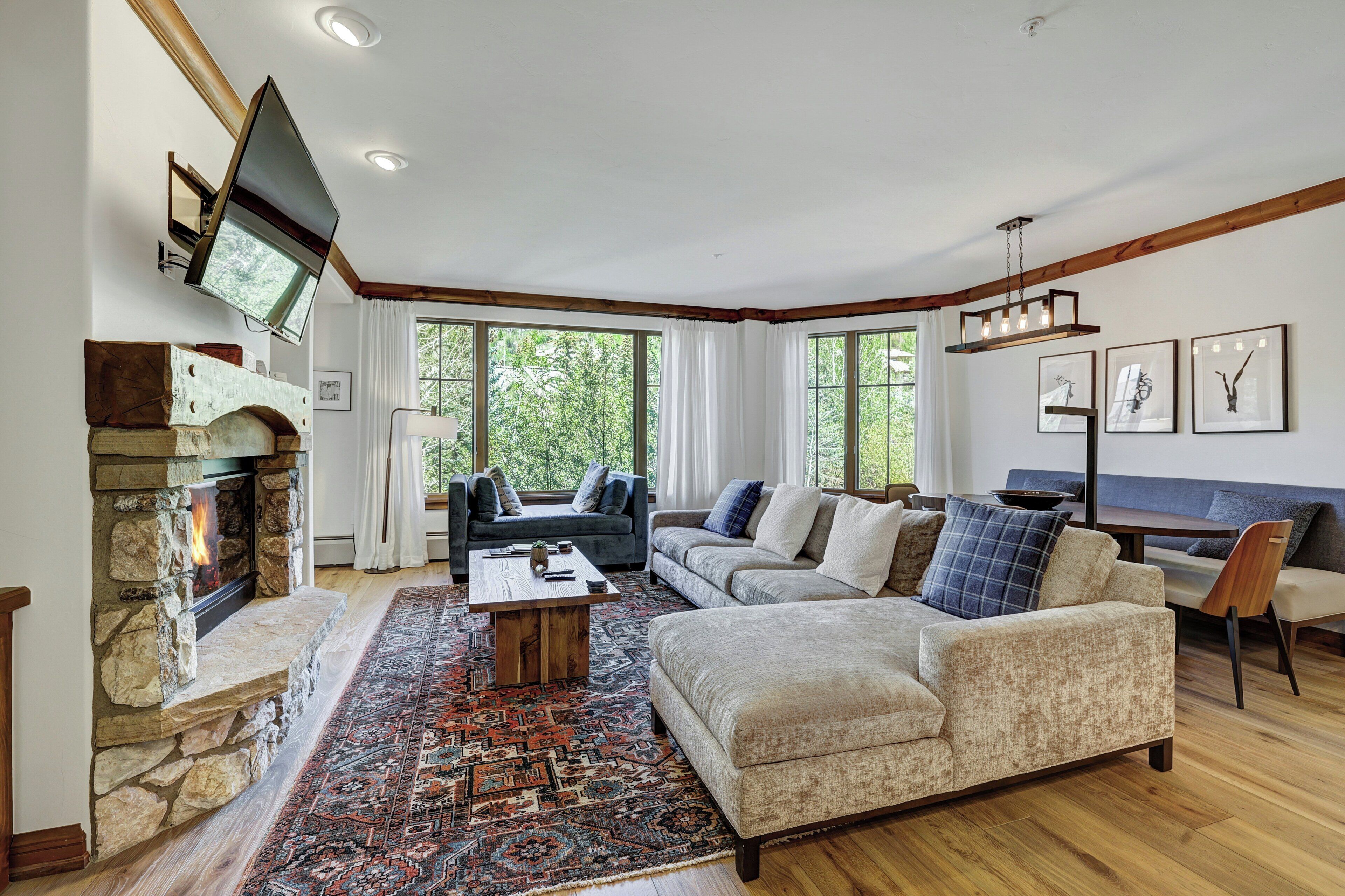 A living room with a stone fireplace, a large sofa, a coffee table, and a rug.