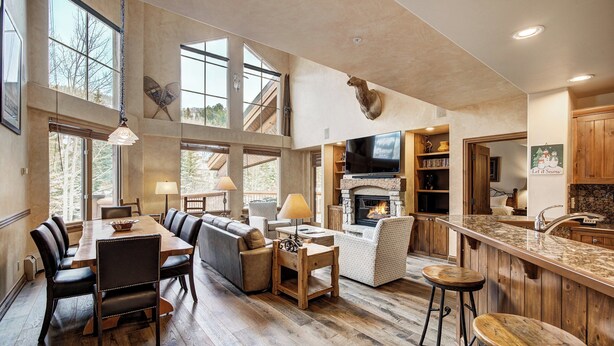 A spacious living area with a fireplace, a dining table with chairs, a sofa, and a television. - Elkhorn Lodge, A Vail Resorts Property (Avon)