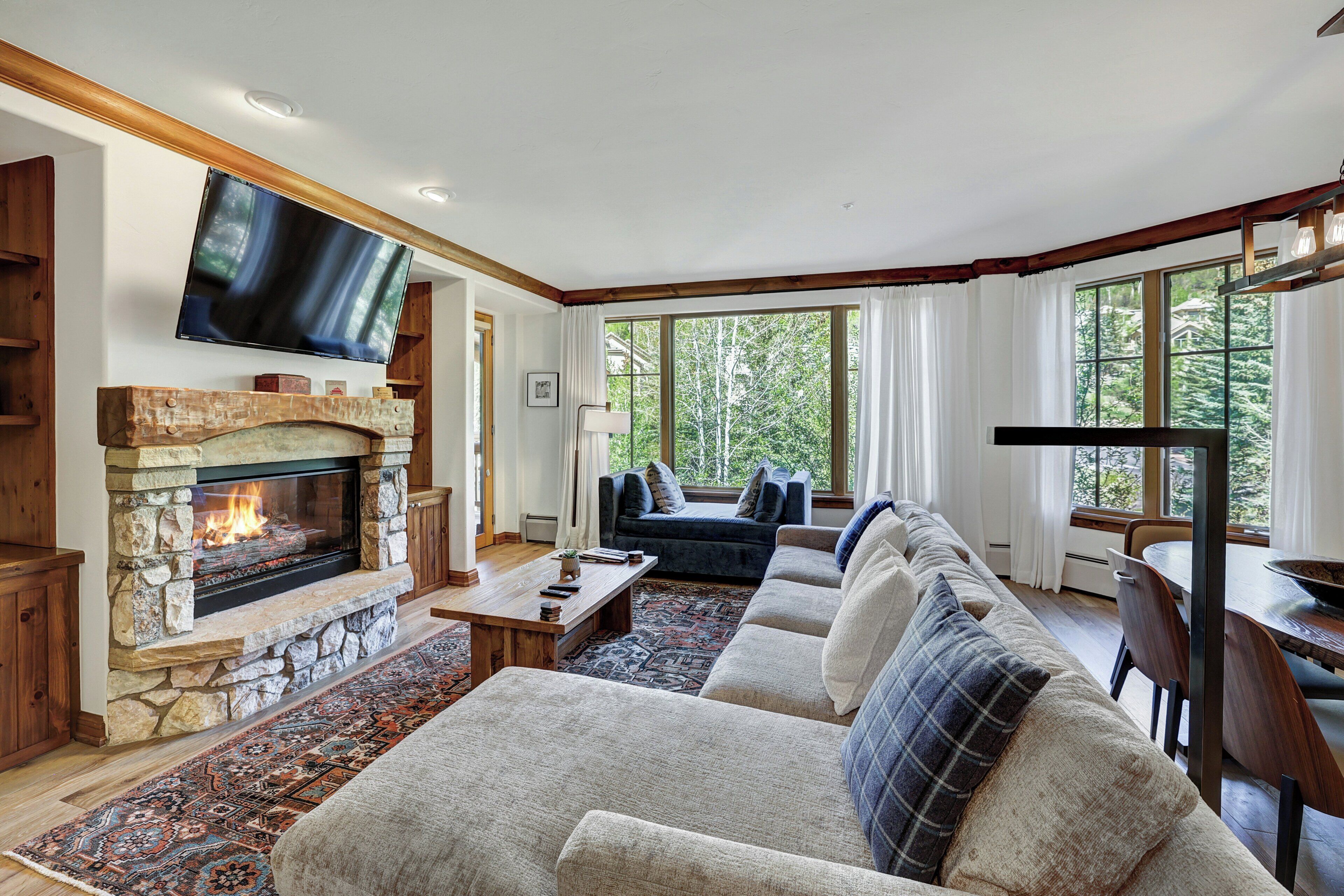A cozy living room with a stone fireplace, a large flat-screen TV, and a comfortable seating area.
